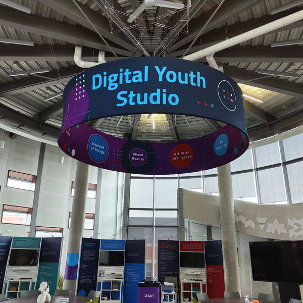 Suspended sign for the Digital Youth Studio showcasing themes like Internet of Things, Mixed Reality, and Artificial Intelligence.