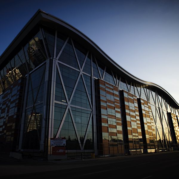 Glass building with a wavy roofline reflecting the warm glow of sunset.