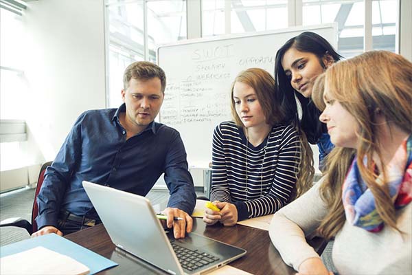 a group of people around a laptop in boardroom