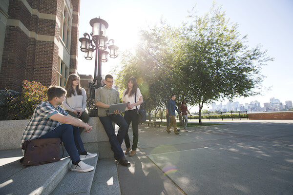 group of people looking at a computer while standing outside