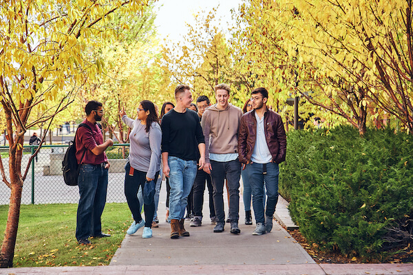 A group of SAIT students walk outside on campus during the autumn.