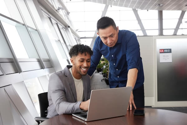 An advisor helps a student on a laptop