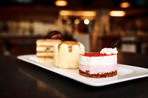 : A close-up of assorted layered desserts on a white rectangular plate