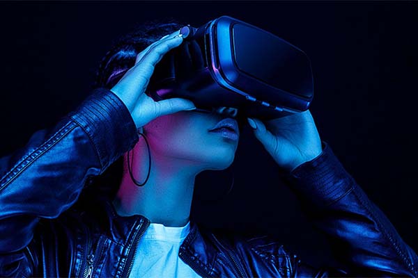 A person wearing a VR headset against a dark, illuminated background, showcasing the immersive experience of virtual reality.