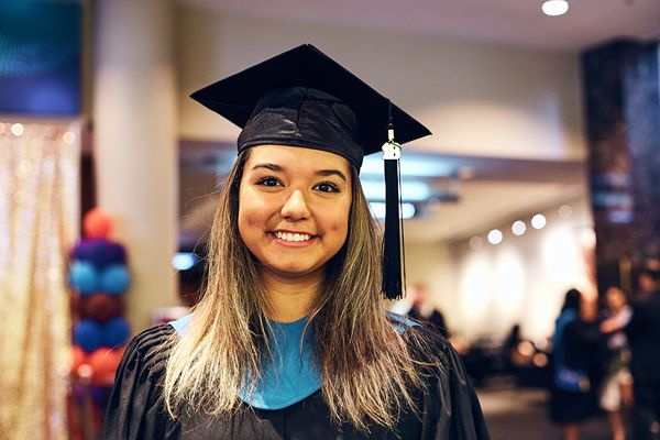 Graduate wearing a cap and gown indoors.