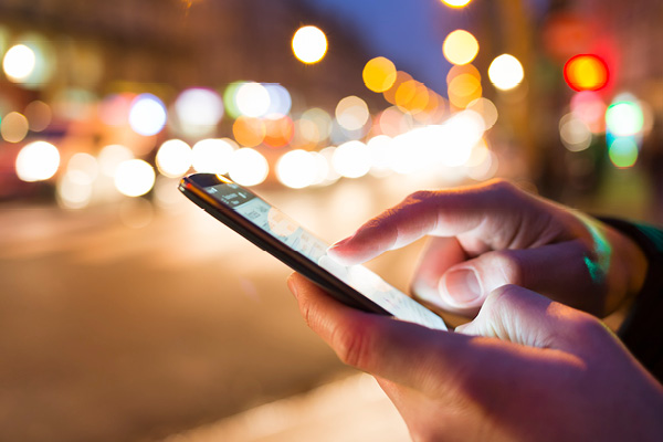 A hand holding a phone with bokeh in the background