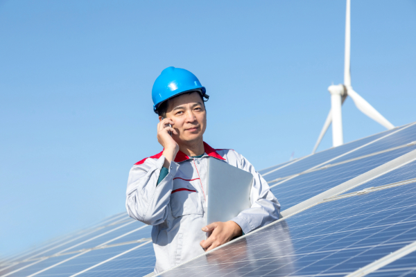 A man checking a solar panel on a roof, on a sunny day.