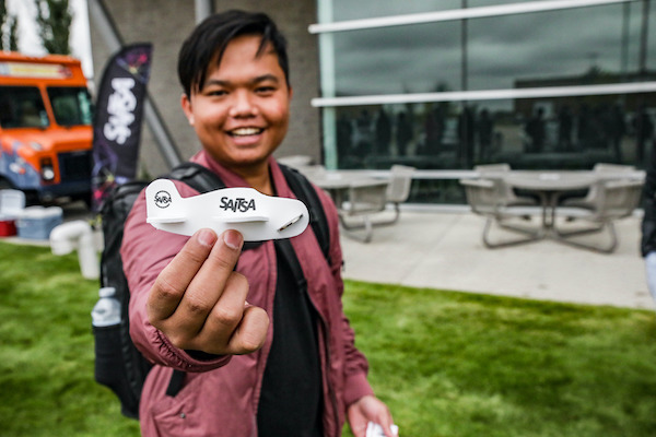 A member of Saitsa holds up a little model airplane with the Saitsa logo on it.