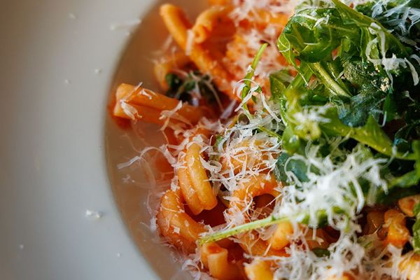 A plate of pasta topped with fresh arugula 