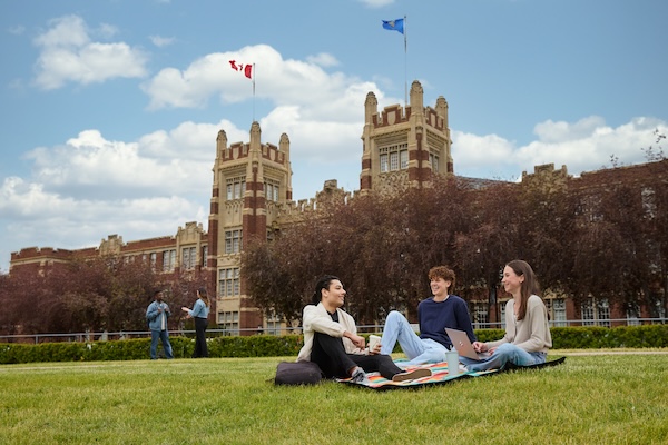 students sitting on the grass infront of a brick building