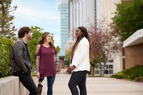 Three people chatting outdoors on campus.