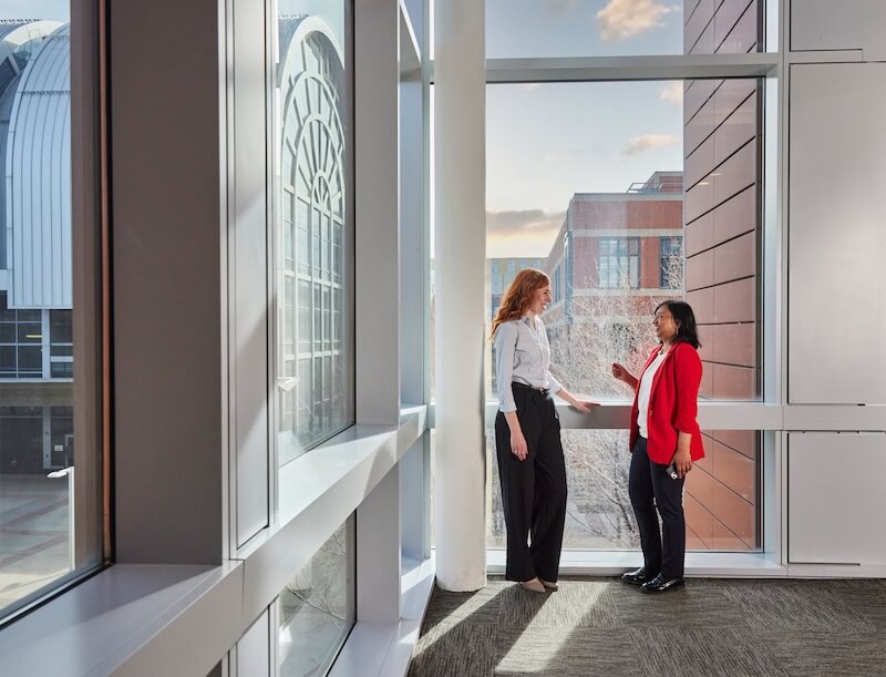 Two people talking at the end of the hallway