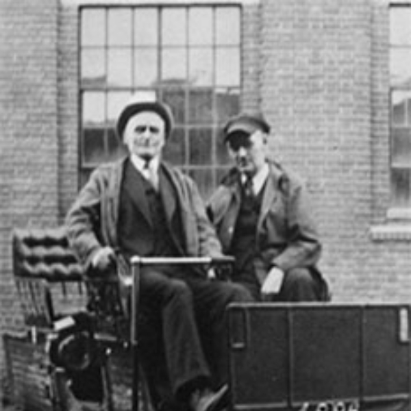 Two individuals sit in a Stanley Steamer posing for a photograph in the 1920s.