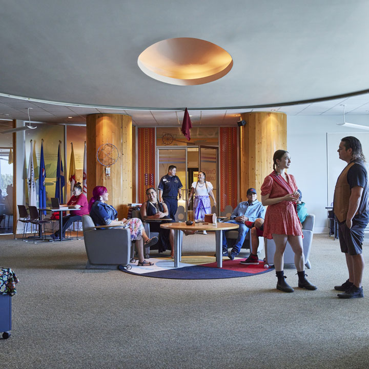 Inside Natoysopoyiis, a vibrant gathering space featuring a diverse group of people engaging in conversation and activities within a modern interior design.