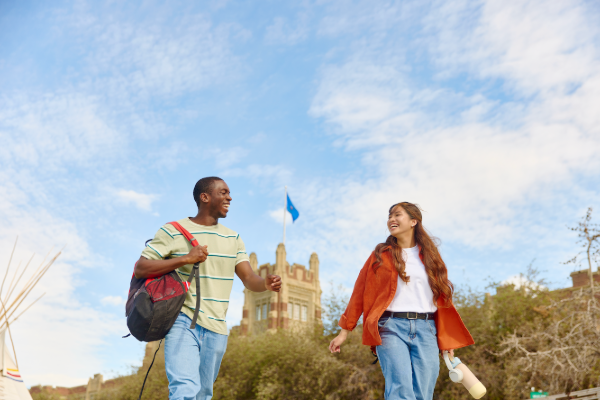 Two students walking outside, with Heritage Hall in the background.