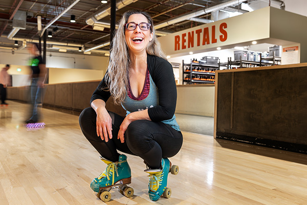 A woman smiling at the camera wearing roller skates