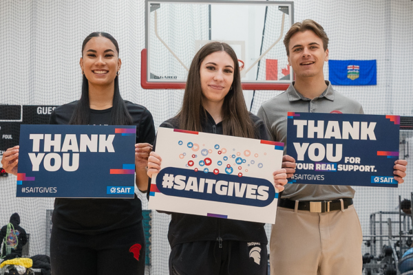 Three students holding up Giving Day signs