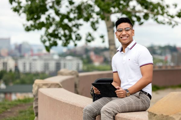 A man sitting down with a laptop in his hands