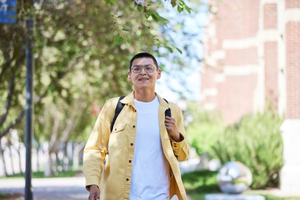 A man wearing a yellow shirt walking outdoors