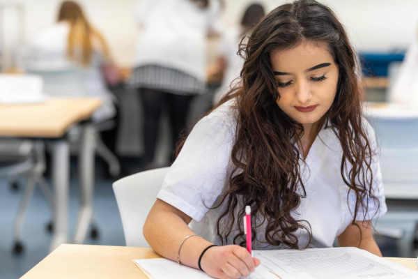 Student writing at desk