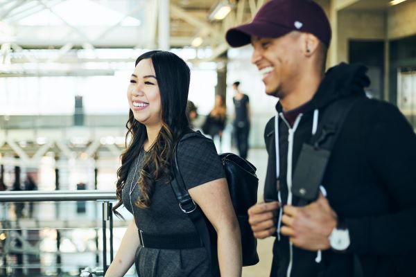 Two people walking indoors with backpacks in a bright, modern building.