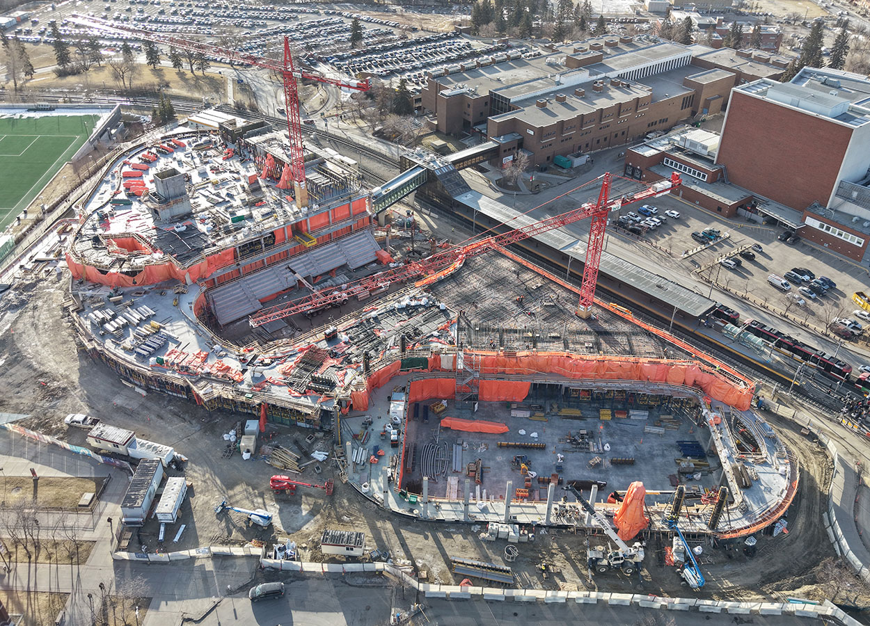 Aerial view of the Taylor Family Campus Centre construction site on Jan. 19, 2026, showing two large red cranes, concrete superstructure, orange tarps and equipment around the building, in progress.