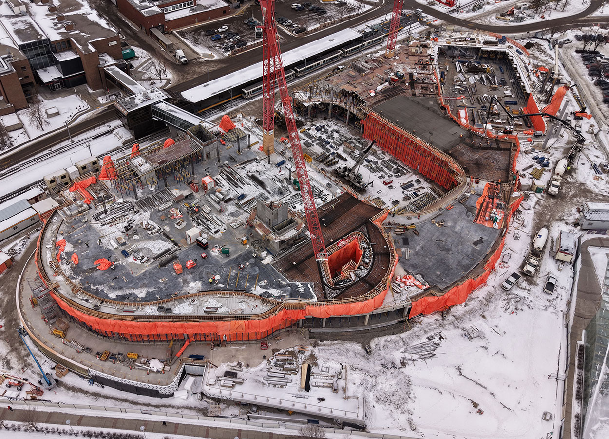 Aerial view of the Taylor Family Campus Centre construction site on Jan. 19, 2026, showing two large red cranes, concrete superstructure, orange tarps and equipment around the building, in progress.
