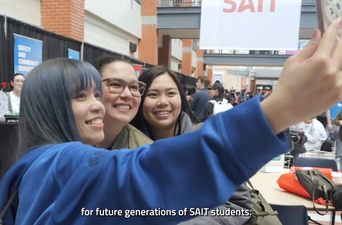 a group of students in taking a selfie together on campus in SAIT's Stan Grad Centre