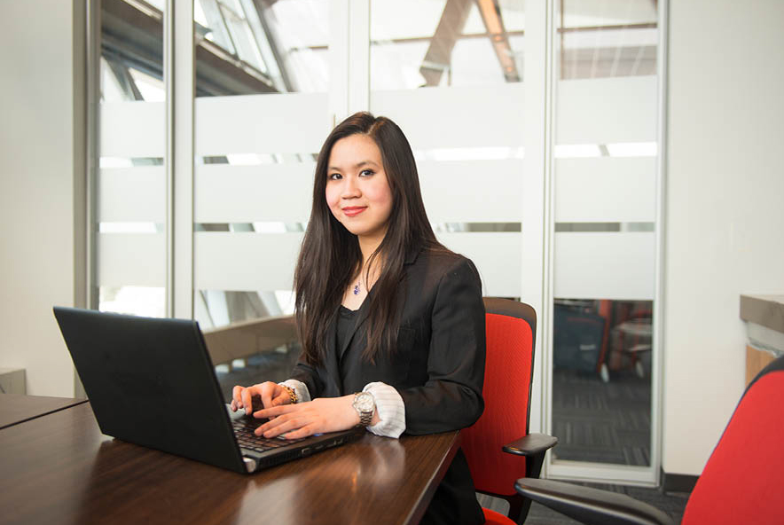 A professional woman working on a laptop in a modern office setting.
