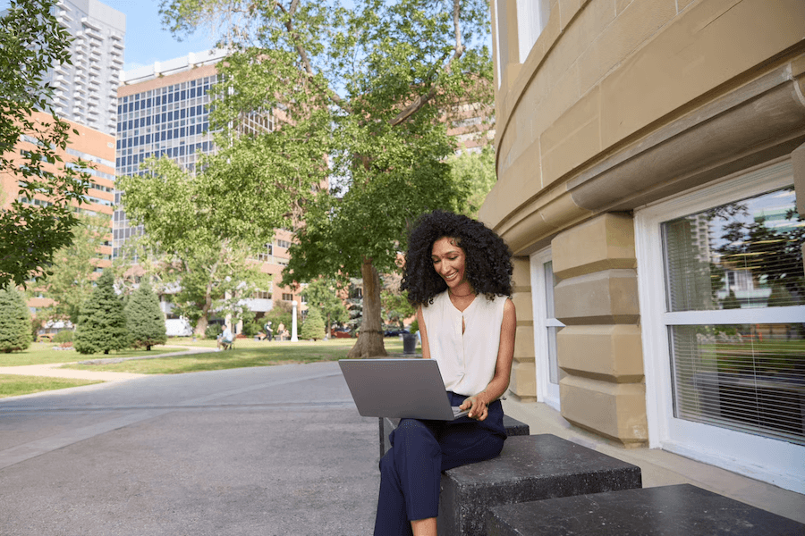 Student sitting outside, working on laptop.