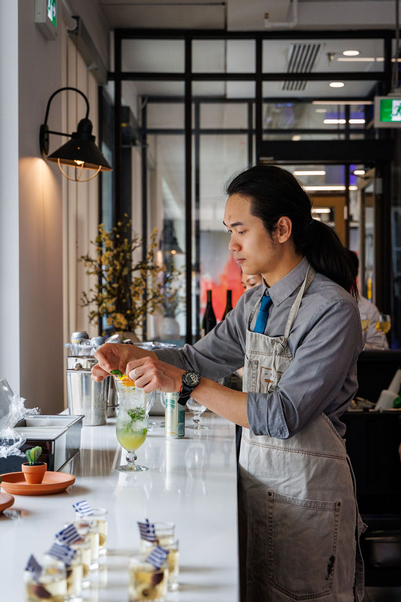 A bartender prepares a cocktail at a stylish bar, showcasing a vibrant drink and the modern ambiance of the establishment.