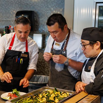 Chefs are preparing and plating food in a professional kitchen setting.