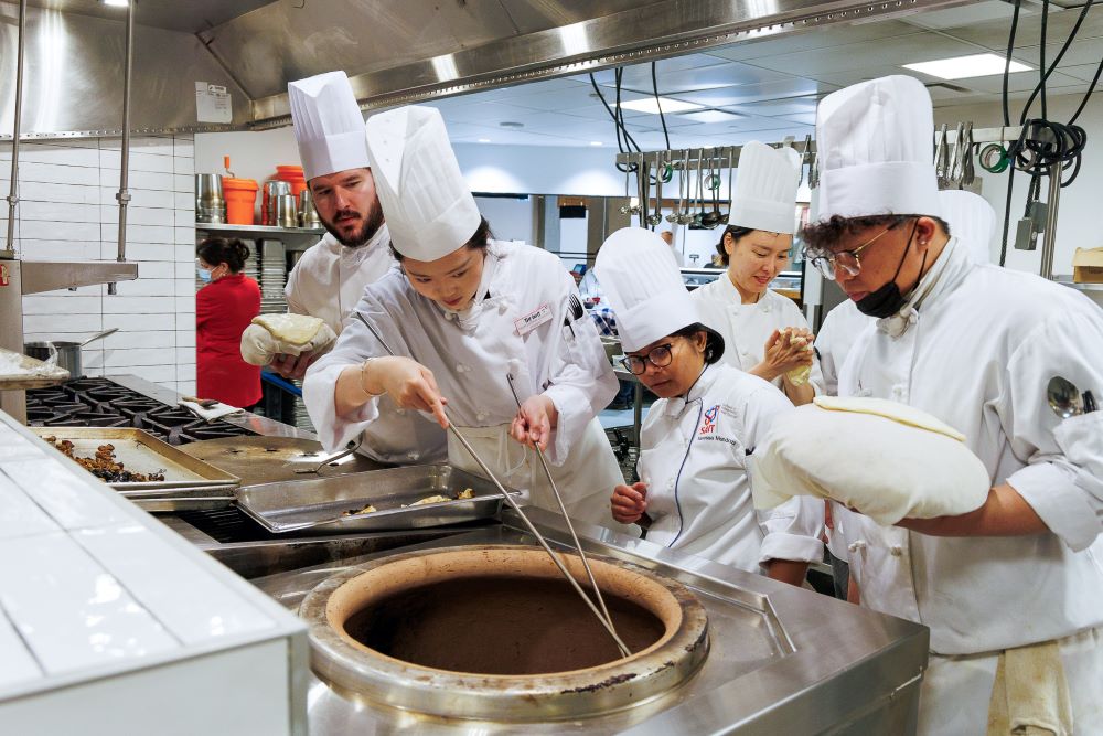 Chefs preparing bread for a traditional clay oven.