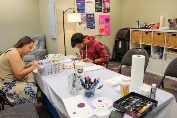 Two students do a craft in the Zen Den, surrounded by art supplies.