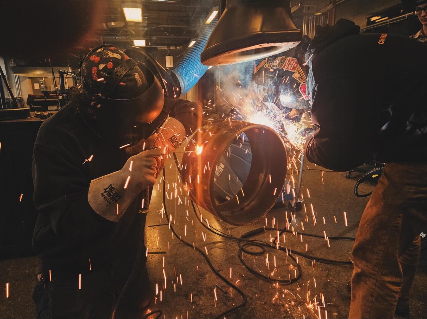 A student wearing a welding mask sauters something. 