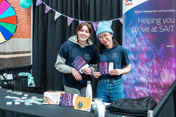 Two students smile beside a booth