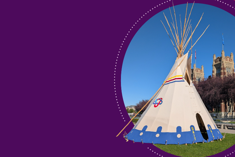 Teepee with a blue base and SAIT logo on a grassy lawn, set against a clear blue sky and a historic campus building in the background.