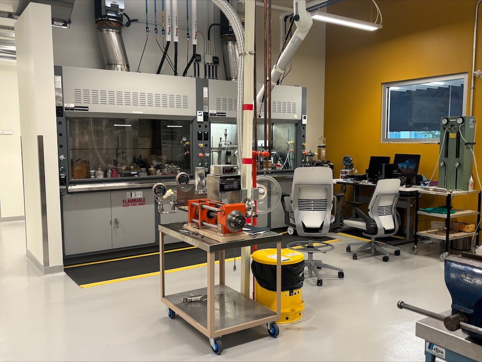 Two men standing at the entrance of the Imperial Energy Innovation Centre, smiling and holding open double doors.