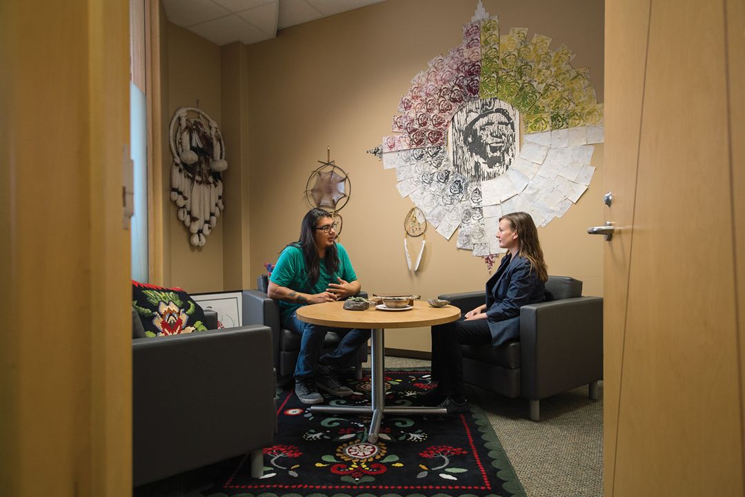 Two people sit facing each other at a small table in a decorated room