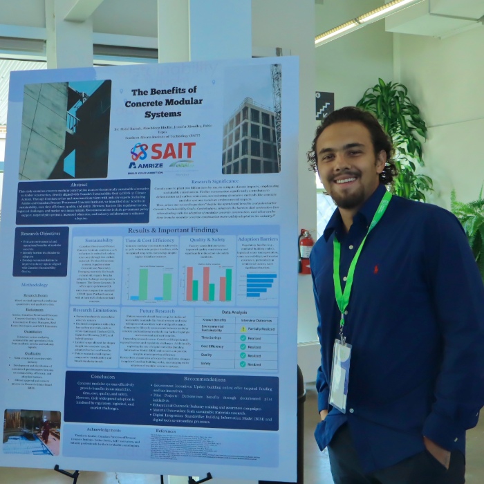 Student standing with research poster, smiling.