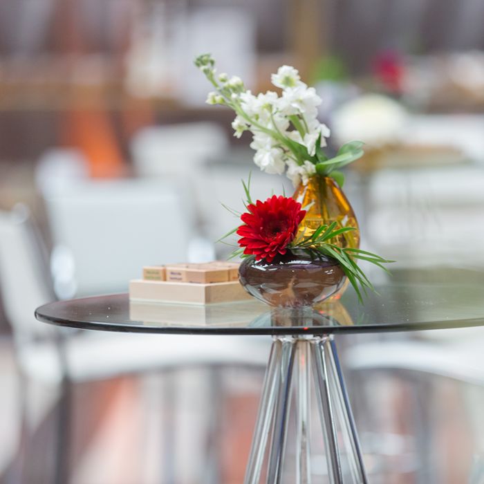 Small glass table with a vase holding white flowers and a red bloom.