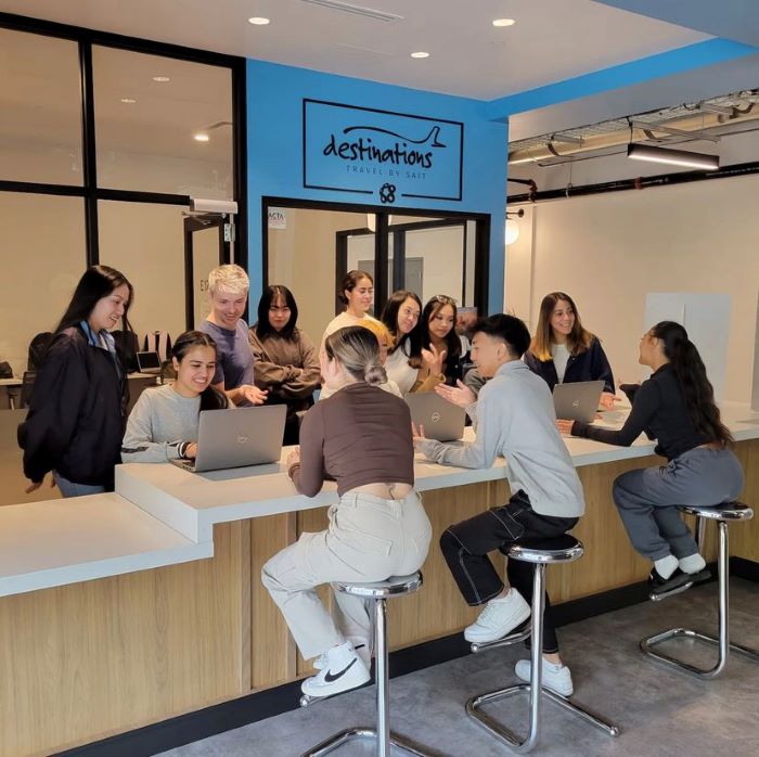 A group of students gathered around a counter working on laptops