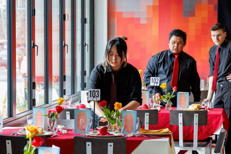 Students members setting tables with flowers, menus, and place settings