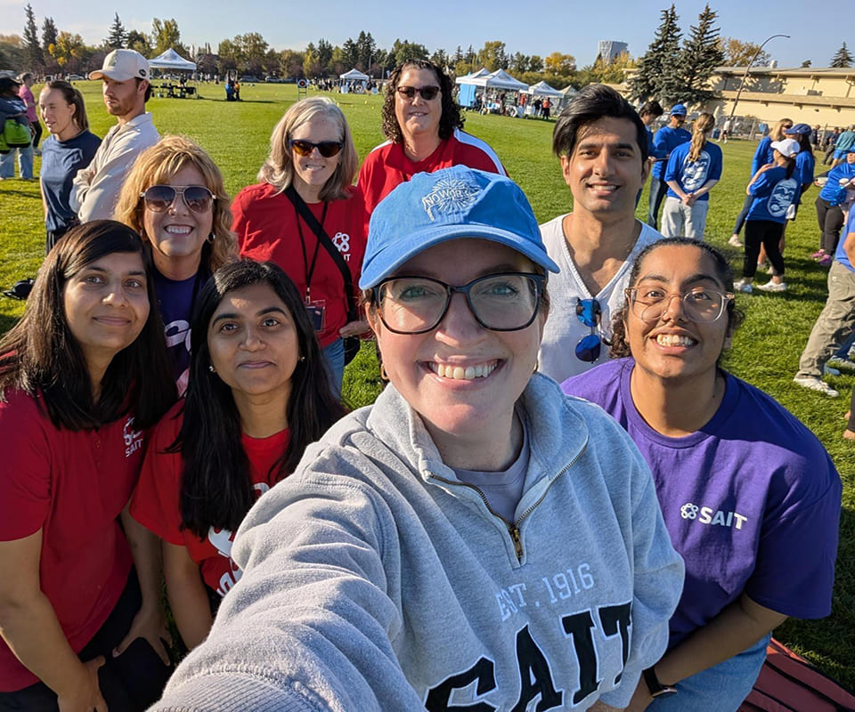 A group of smiling individuals in casual clothing gathered outdoors at a community event showcasing unity and enthusiasm.