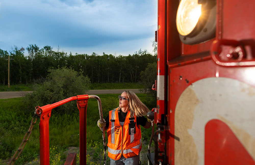 Leslie Lukan standing on steps of train engine as it is moving