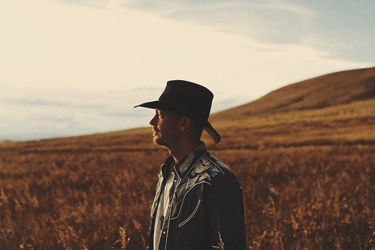 Profile of Paul Brandt standing in the rolling prairies.