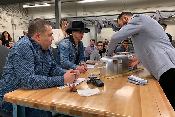 Student presenting project to an instructor and Paul Brandt.