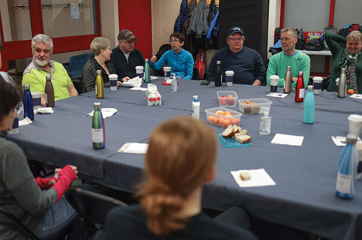 A group of Youquest members sit around a large square table.