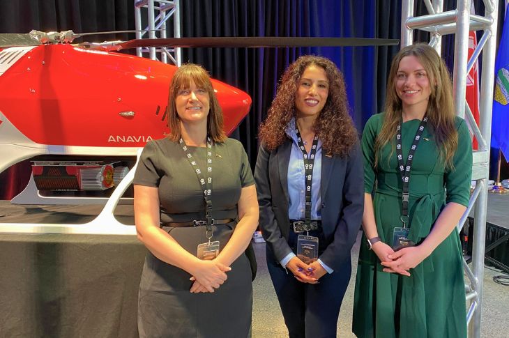 three women posing in front of heavy-lift, long-range drone