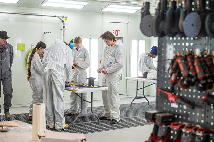 Group of students standing around a table while wearing protective gear